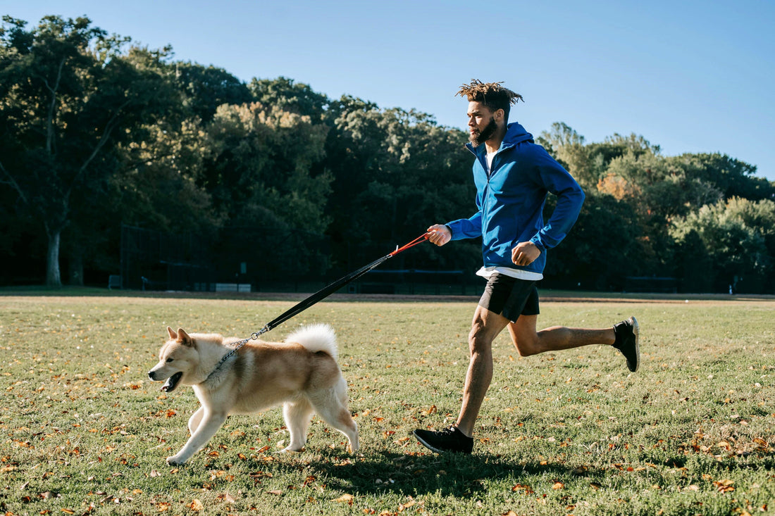 Man runs with dog on a leash.